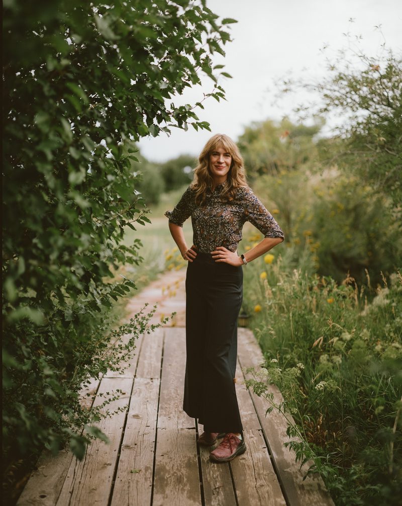 Dr. Anne Metz standing on a wooden boardwalk between summer greenery